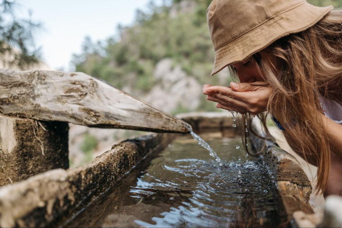Someone drinking water from a wooden water flow