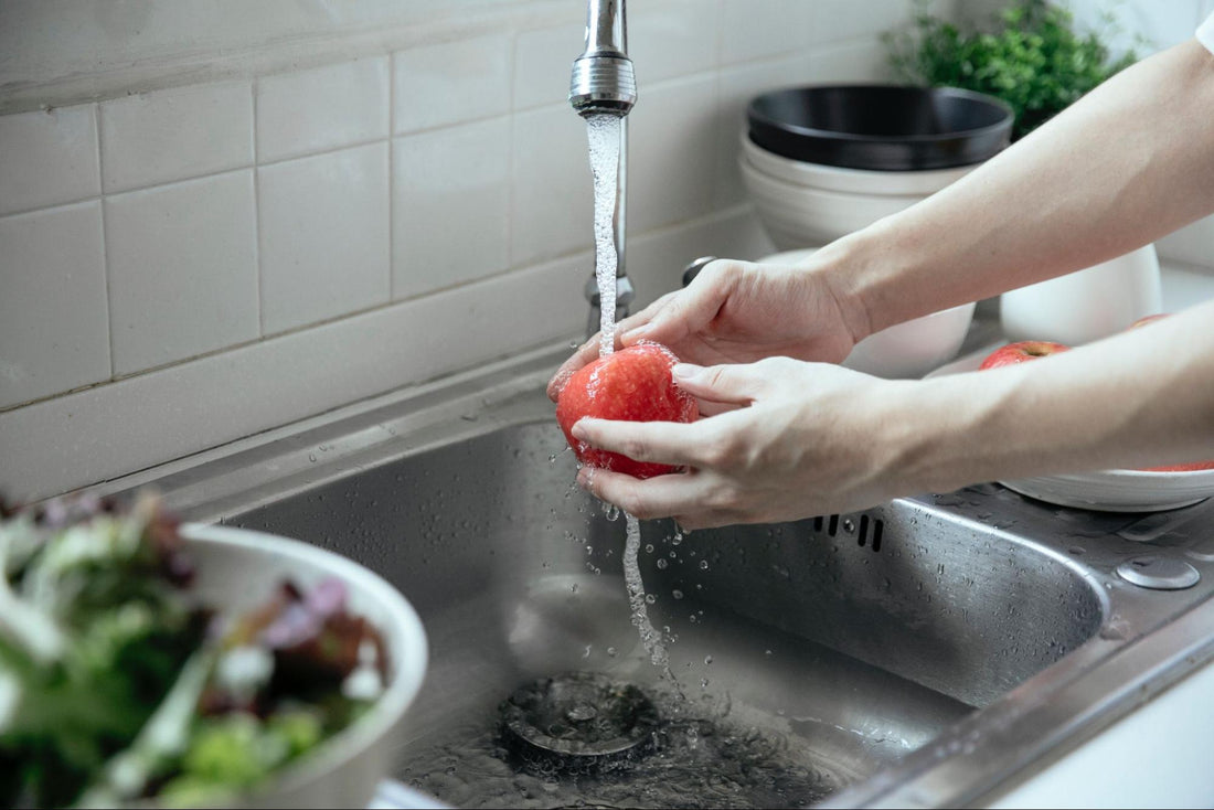 A person washing fruit using tap water